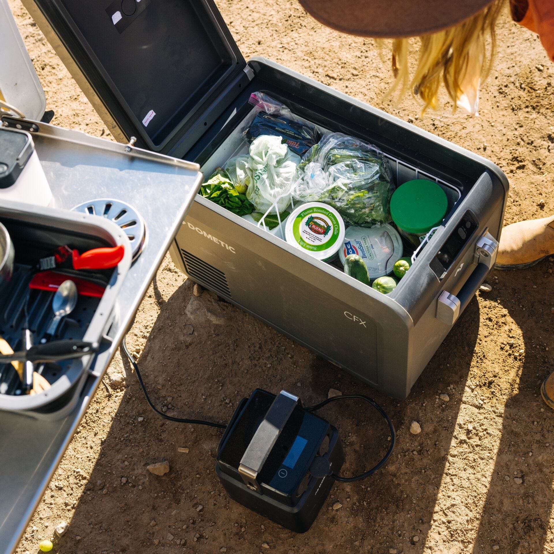 Portable cooler with food items on a dirt ground