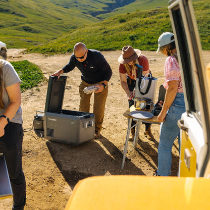 Group of people preparing for an outdoor adventure with a cooler and camping gear.