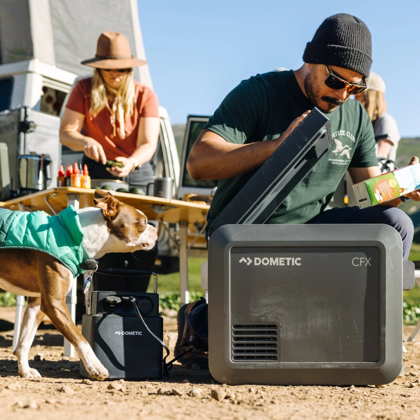 Person using a Dometic CFX portable power station outdoors with a dog nearby.